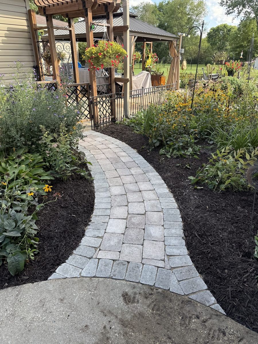Curved paver walkway with mulch beds and flowering plants