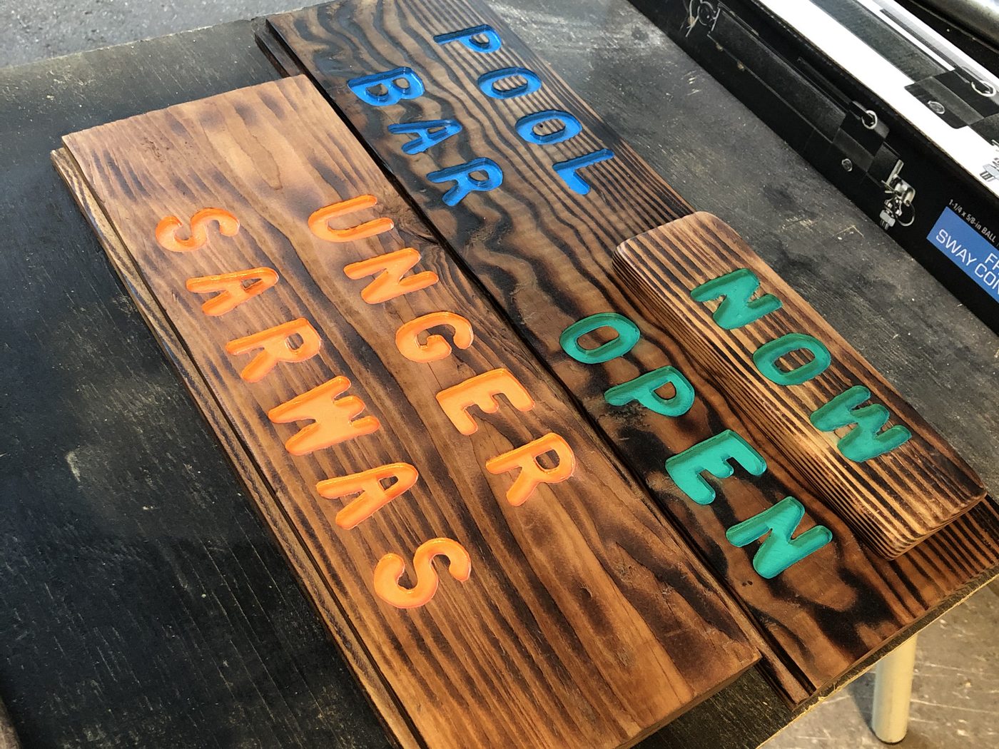 Custom burnt-wood sign reading Pool Bar Open