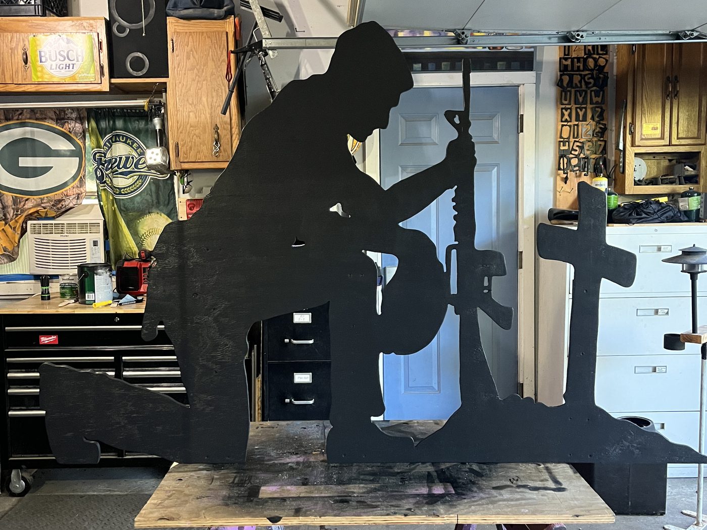 Custom laser-cut memorial silhouette sign of a kneeling soldier and battlefield cross